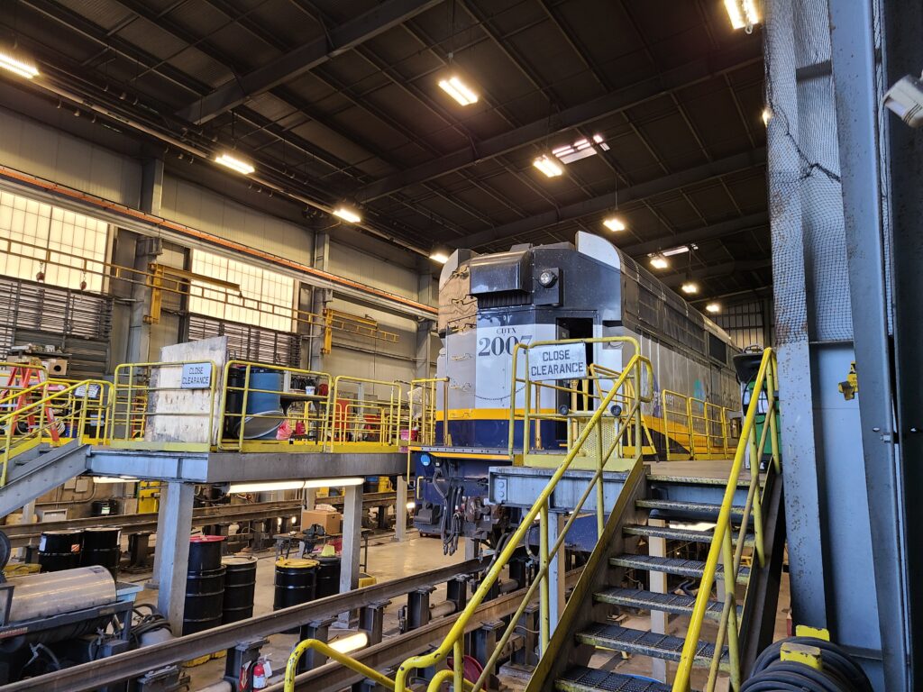 Locomotive in a maintenance shop with yellow-railed steel access platforms and stairs