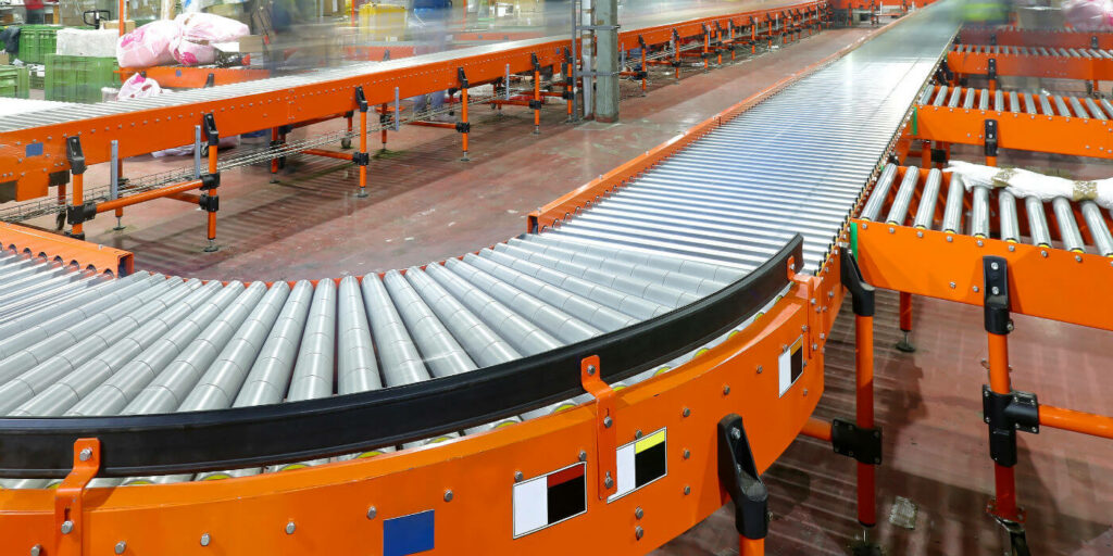Orange roller conveyor lines with a curved section in a warehouse