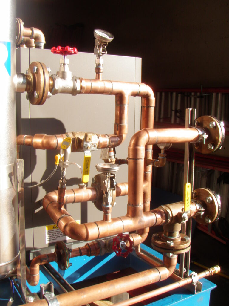 Copper pipe loop with flanged valves and a pressure gauge on a blue equipment skid