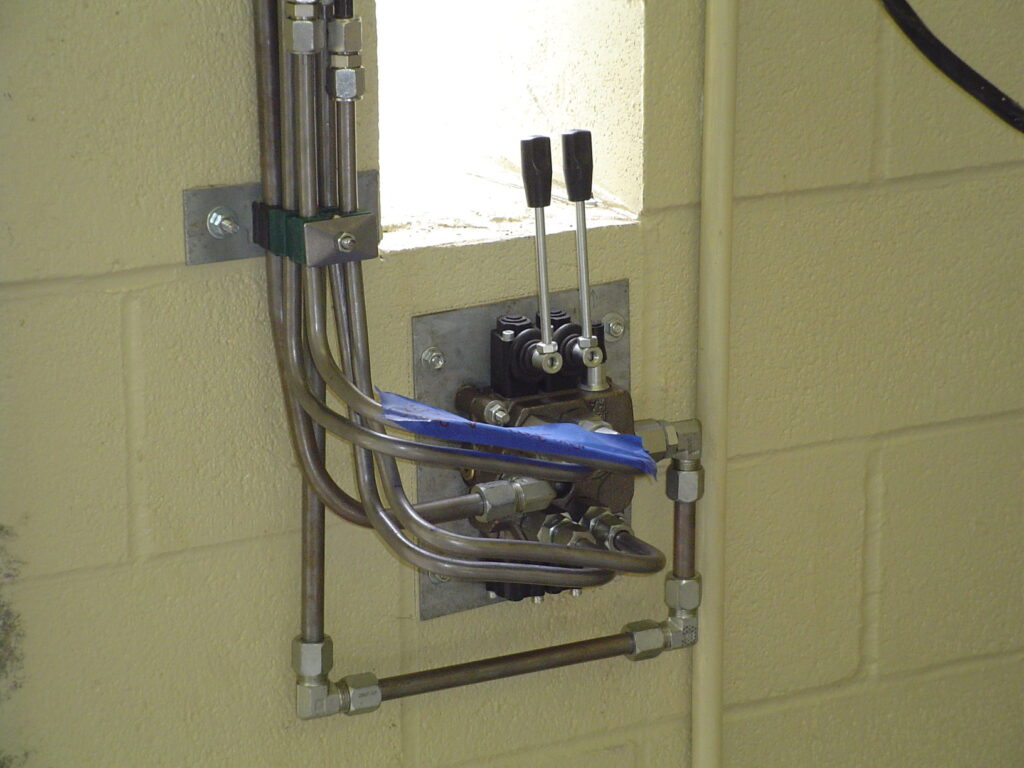 Two-lever hydraulic control valve with steel tubing mounted on a block wall